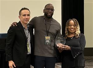 Picture of Marcus Campbell and Pat Savage-Williams holdingan award with David Gonzales.
