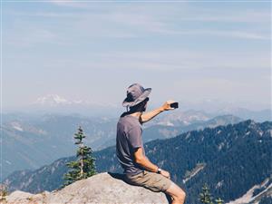 Man taking picture on the top of a mountain 